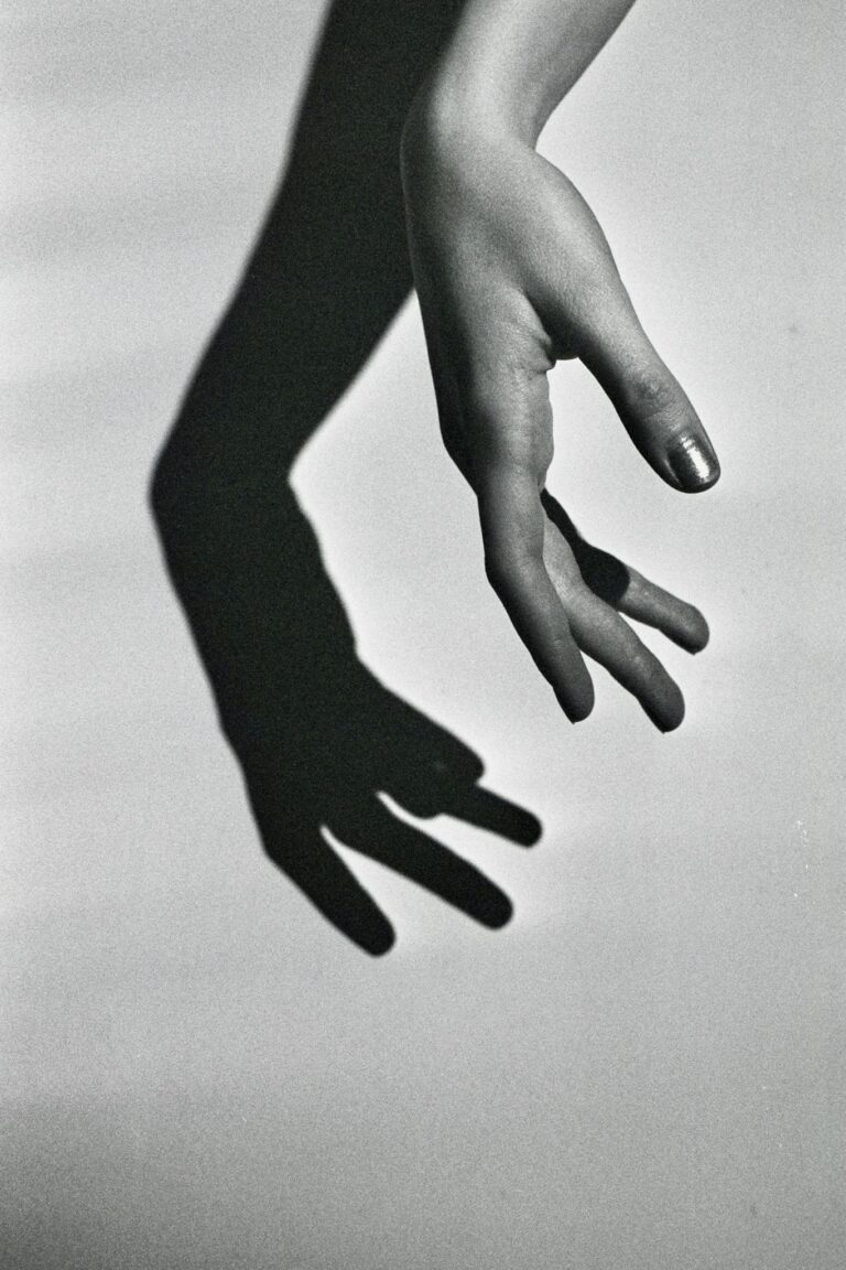 Monochrome photo of a hand and its shadow, creating a striking visual effect.